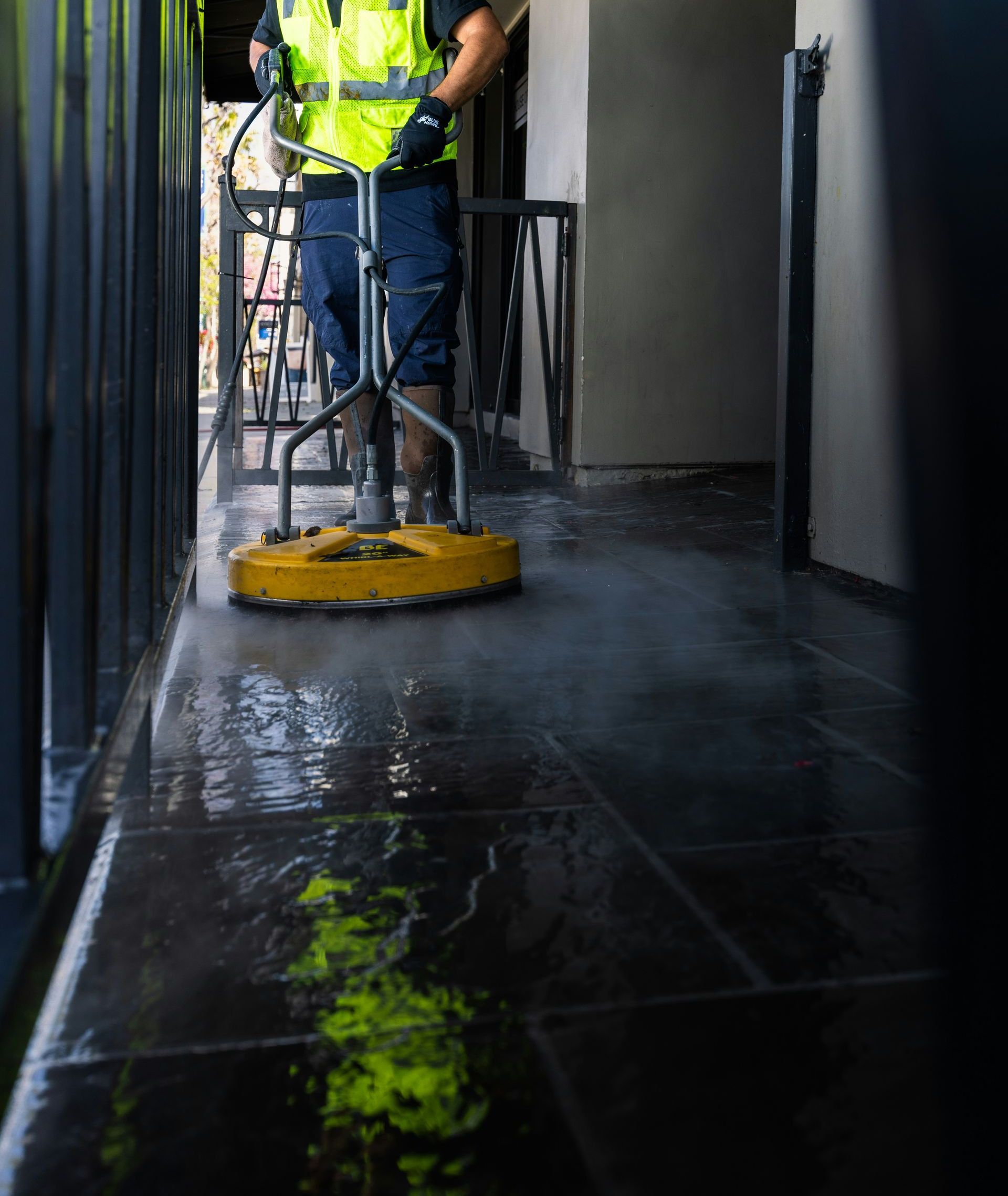 a man in a yellow vest is cleaning the floor